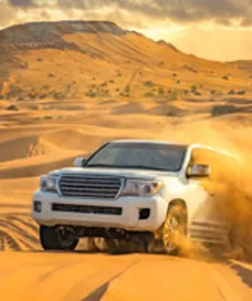 White 4x4 desert safari dubai vehicle racing across stunning dunes in Dubai under a vibrant sunset