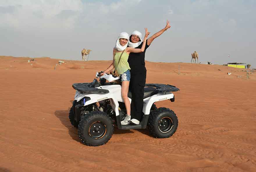 A Yamaha quad bike is parked on a dirt trail, with two ladies getting ready for an off-road adventure.