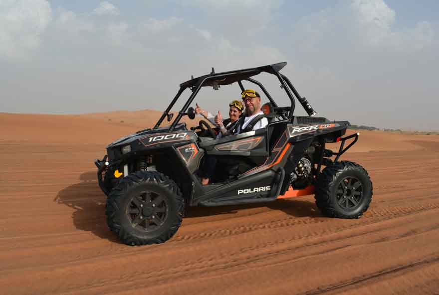 Couple driving a black buggy and stopped for Posing a dune buggy tour in Dubai