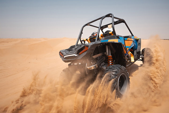 Someone riding Dune buggy in the Dubai desert, leaving a cloud of sand dust behind