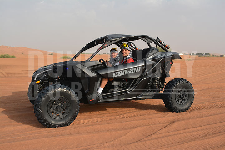 Someone riding Can- Am in the desert, leaving a cloud of sand dust behind