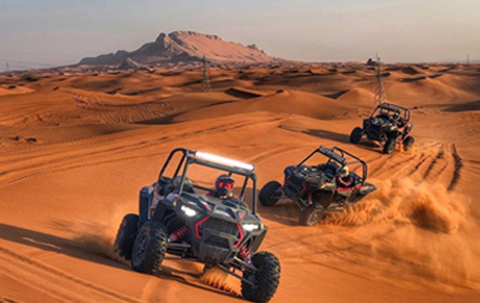 A Group Of Riders Riding Dune Buggies In A Row, Crossing The Sandy Dunes.